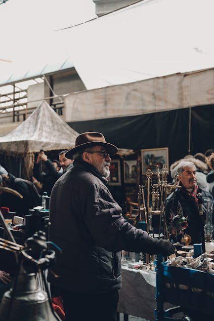 A wide view of a market stall at Brixton Market displaying a colorful array of cleaning tools and supplies arranged in neat stacks and hanging displays. There are multiple plastic buckets and bowls in